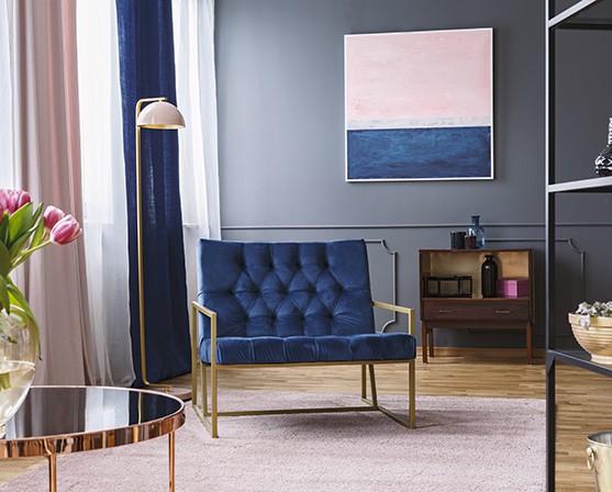 Boutique hotel interieur stijl blauwe velours stoel gouden frame blauw roze woonkamer chique messing sierlijsten lambrisering
